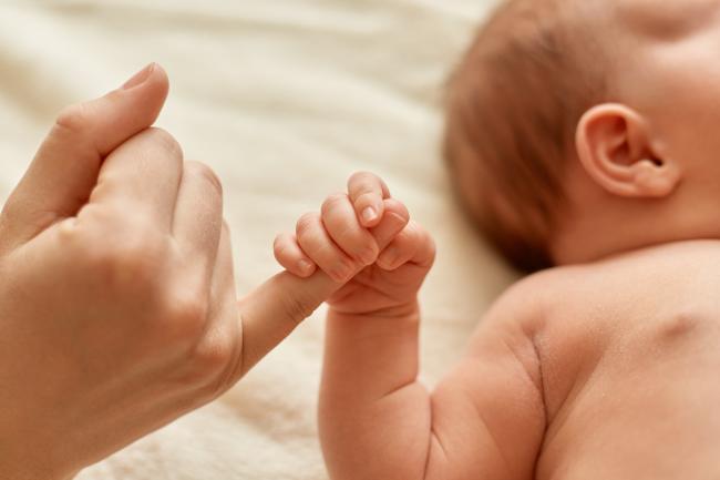 Mano de bebé toma el dedo de una persona adulta