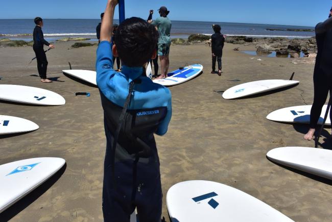Niños y niñas se preparan para surfear. 